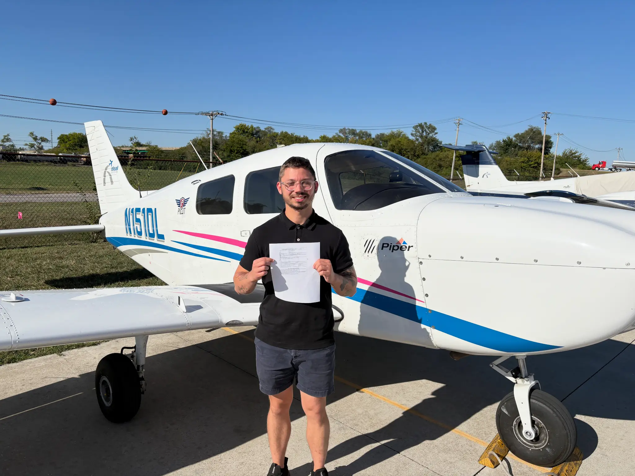 Student holding a certificate in front of a Piper aircraft